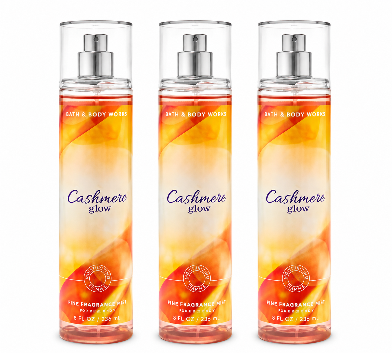 Three Bath & Body Works CASHMERE GLOW Fine Fragrance Mist bottles arranged in a premium 3-pack display on pure white background, showcasing the warm amber, peach and golden fragrance collection.