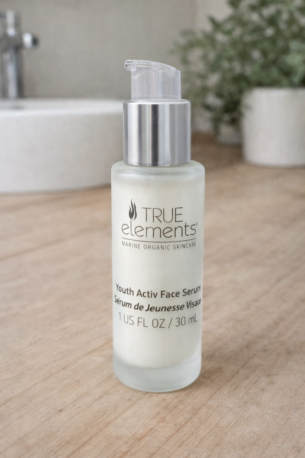 True Elements Youth Activ Face Serum bottle on a wooden surface with a bathroom background